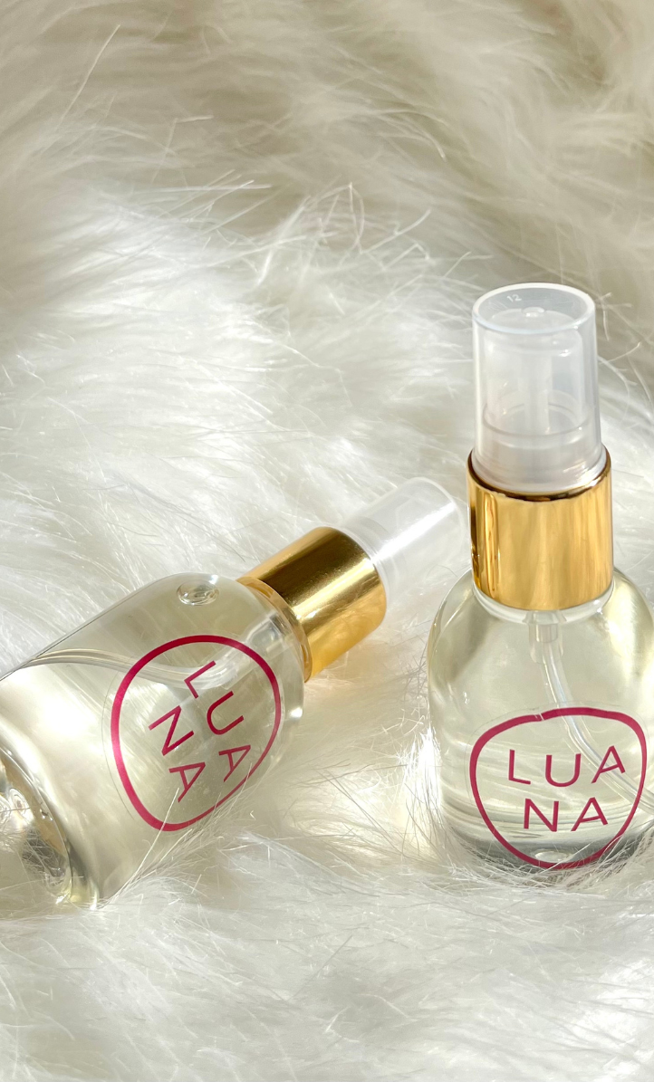 Perfume Folgora Luana, dos botellas de fragancia de 49ml con tapas doradas sobre fondo blanco peludo.