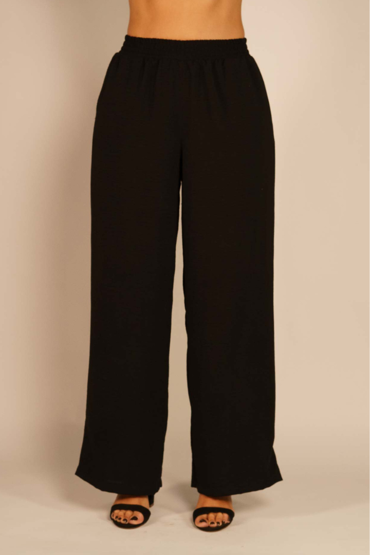 Pantalón Brena negro de seda con cintura elástica y pierna ancha, ideal para look casual o elegante.