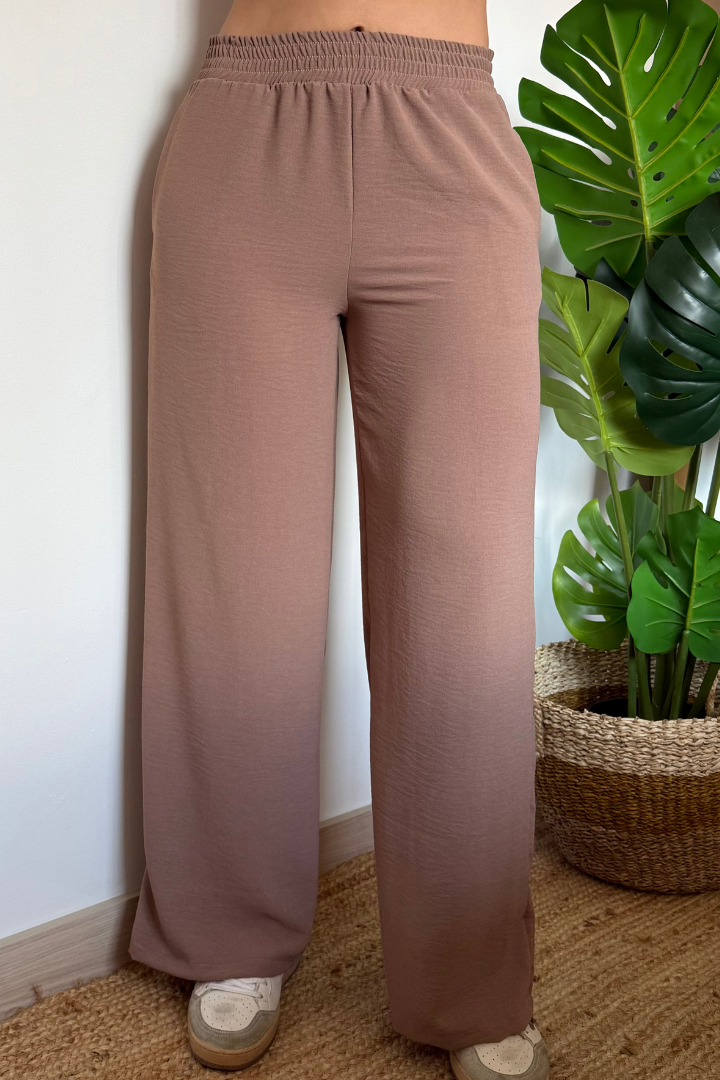 Pantalón Brena moka de seda moma, pretina resortada, tiro alto y bota ancha en estudio con planta verde. Ideal para mujer.