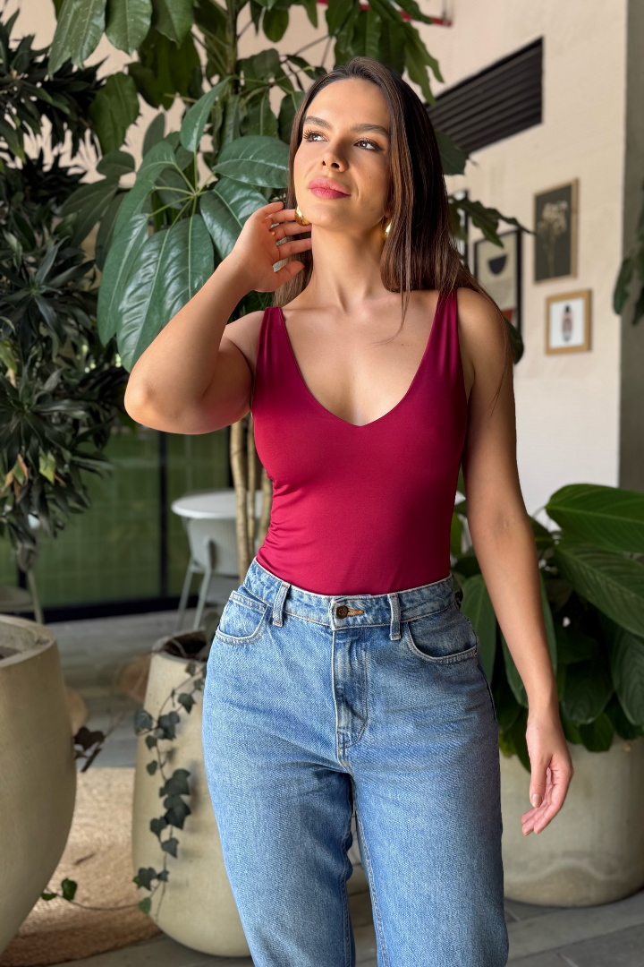 Modelo colombiana luciendo el Body Ryna Vino de Folgora con escote en V y jeans azules. Elegante y cómodo.