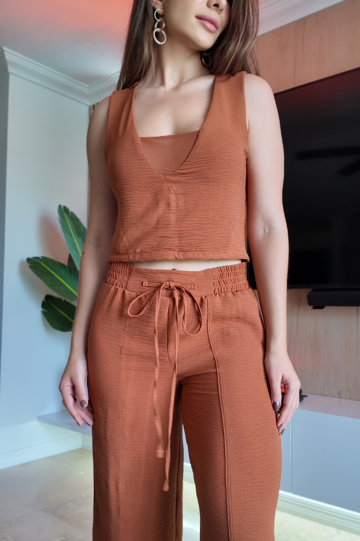 Blusa Aroa Terracota y pantalón a juego en una modelo de pie, resaltando la textura de la tela y el ajuste casual.