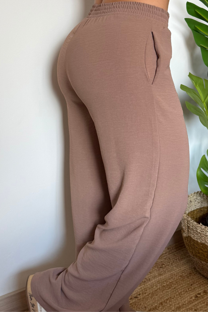 Pantalón Brena moka de mujer, tiro alto con pretina elástica y bolsillos laterales, de seda. Vista lateral trasera.