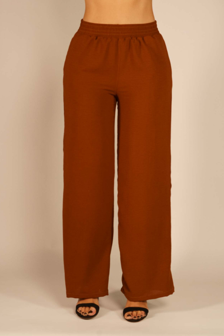 Pantalón Brena café para mujer, corte paol, pretina resortada, tiro alto, modelo de pie.