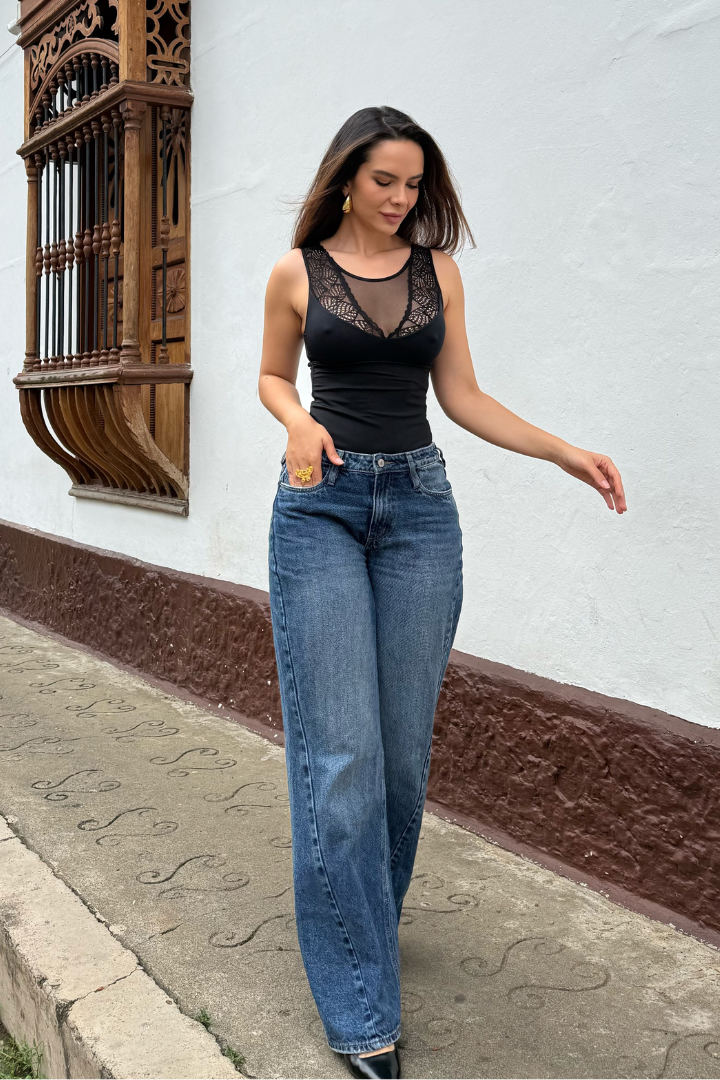 Modelo con body Aura negro de control de abdomen y encaje, combinado con jeans, caminando en exterior.