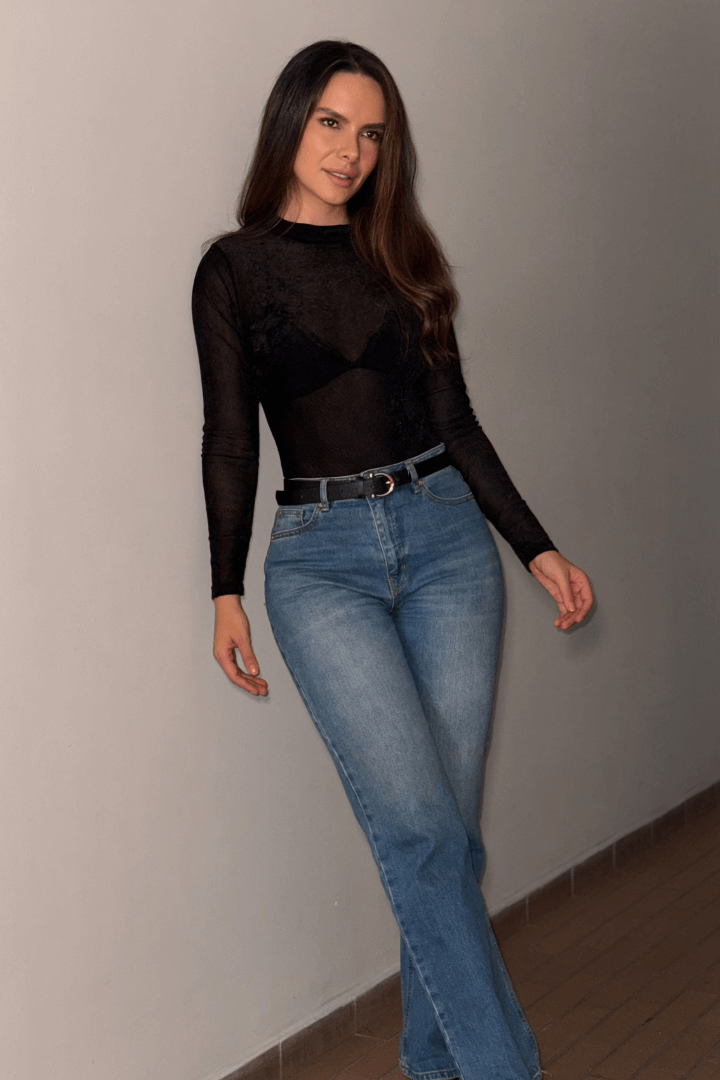 Modelo en body Brisa negro afelpado, manga larga, cuello alto, con jeans y cinturón. Destaca la textura translúcida.