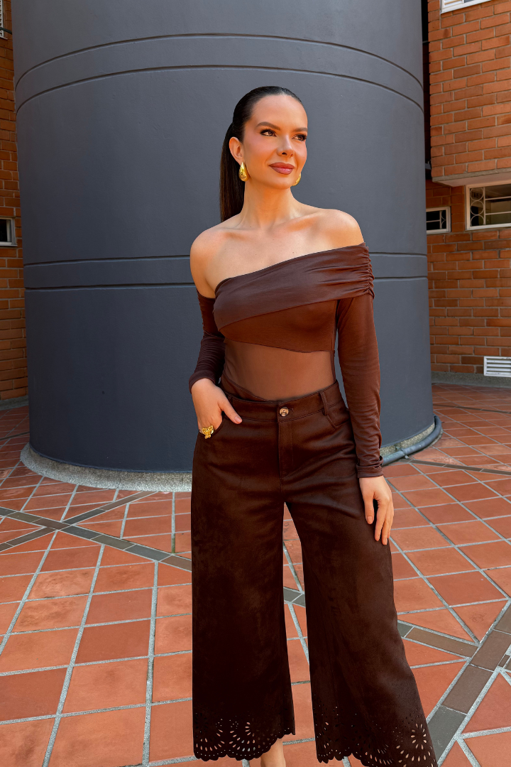 Modelo con Body Aria Marrón de manga larga, un hombro descubierto y pantalón ancho marrón con detalle calado.
