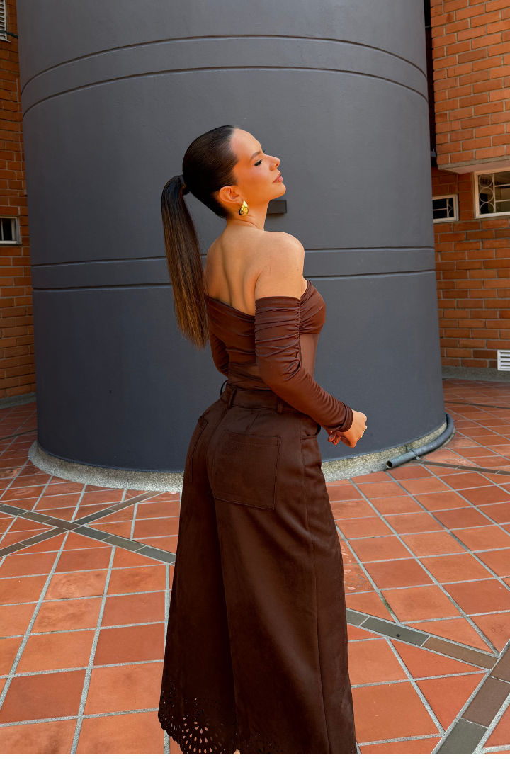 Mujer usando Body Aria Marrón de manga larga y escote barco, con pantalón oscuro. Prenda elegante hecha en Colombia.